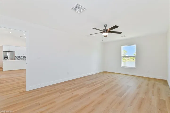 Empty room with light wood-style flooring, ceiling fan, and baseboards