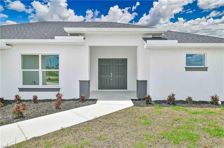 Doorway to property featuring a shingled roof and stucco siding
