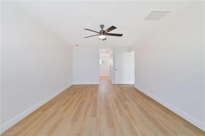 Empty room with baseboards, light wood-type flooring, and a ceiling fan