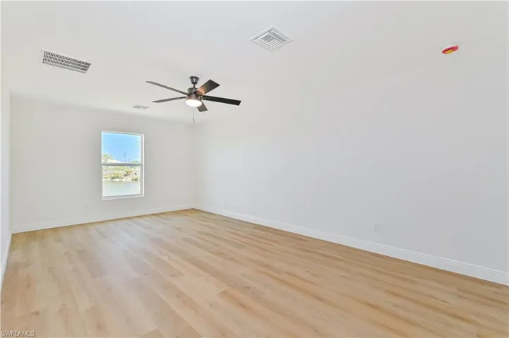 Unfurnished room with baseboards, a ceiling fan, and light wood-style floors
