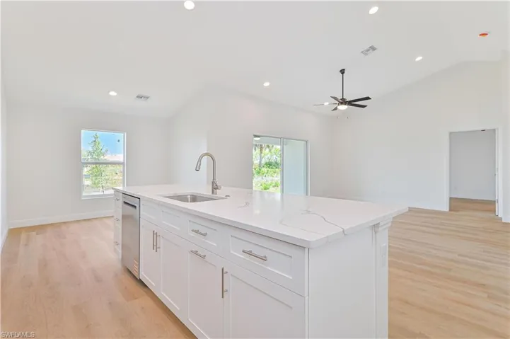 Kitchen with a sink, stainless steel dishwasher, ceiling fan, light wood-style flooring, and recessed lighting