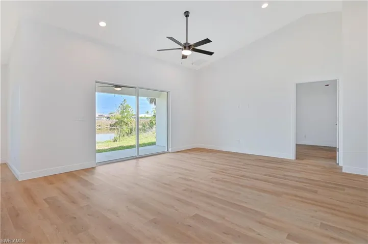 Empty room with a ceiling fan, high vaulted ceiling, light wood-style floors, baseboards, and recessed lighting