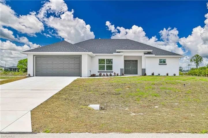 View of front of property with an attached garage, stucco siding, driveway, a front lawn, and a shingled roof