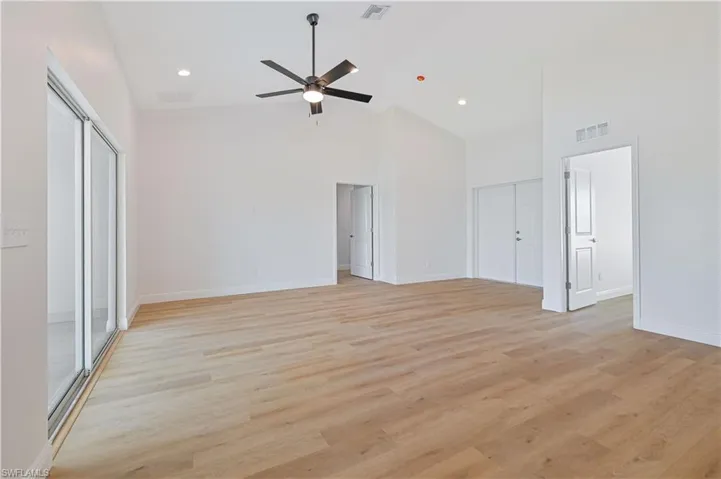 Unfurnished living room with high vaulted ceiling, ceiling fan, light wood-style floors, baseboards, and recessed lighting