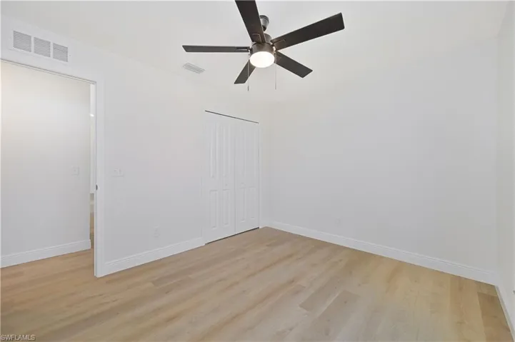 Spare room featuring light wood-style floors, a ceiling fan, and baseboards