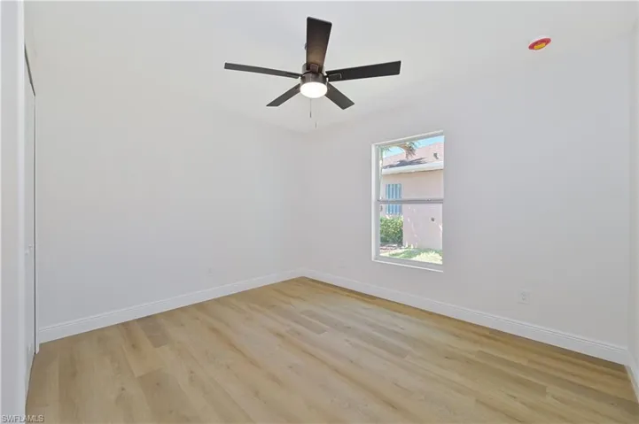 Spare room with light wood-type flooring, baseboards, and a ceiling fan