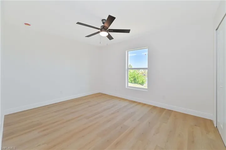 Unfurnished room featuring baseboards, light wood finished floors, and ceiling fan