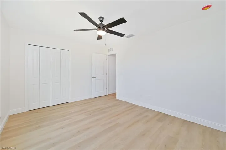 Unfurnished bedroom featuring light wood-style flooring, baseboards, and a closet