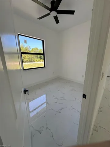Spare room featuring light marble finish floors and ceiling fan