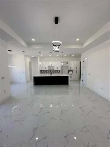 Unfurnished living room with a raised ceiling and recessed lighting