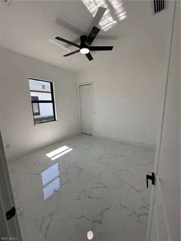 Unfurnished bedroom featuring light marble finish flooring and ceiling fan
