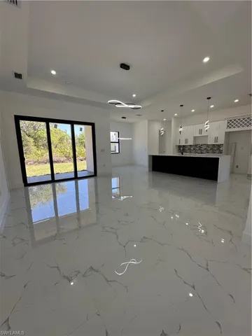 Unfurnished living room featuring a tray ceiling and recessed lighting