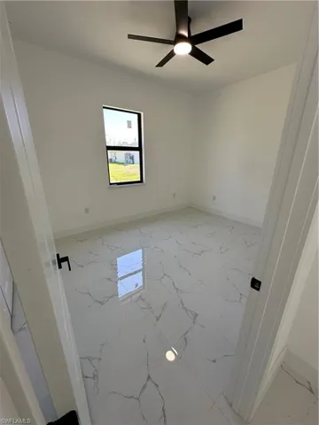 Spare room featuring light marble finish flooring and a ceiling fan