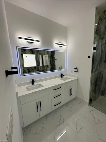 Full bathroom with double vanity and a marble finish shower