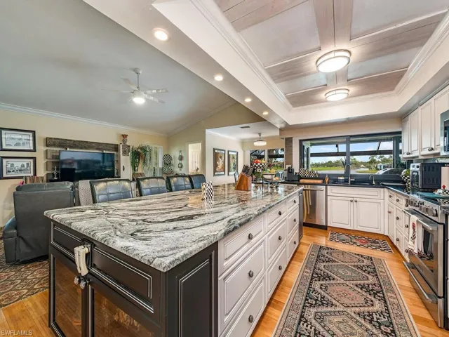Kitchen featuring a kitchen island, light stone counters, white cabinets, and stainless steel appliances