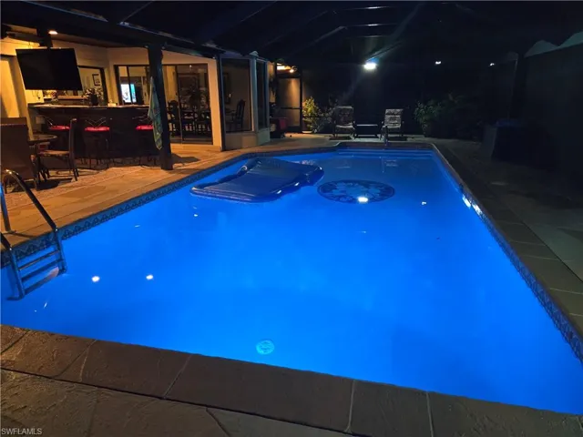 View of swimming pool with a bar, a lanai, and a patio