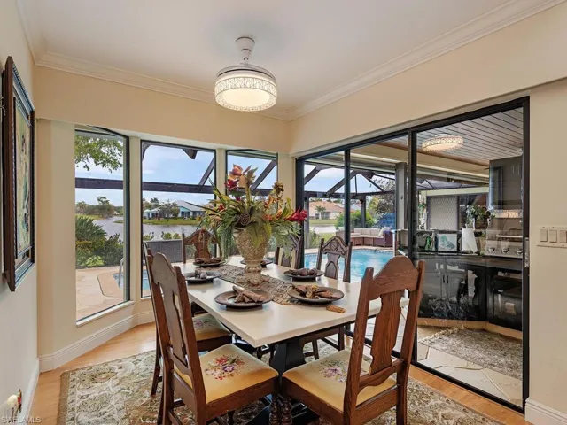 Dining space featuring light hardwood / wood-style flooring, a water view, crown molding, and plenty of natural light