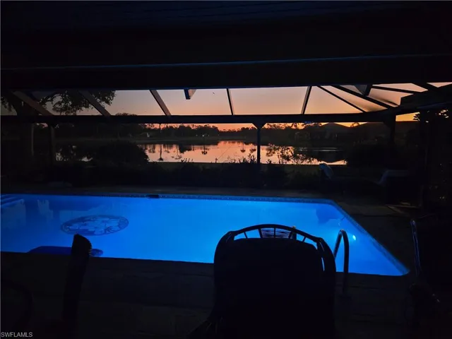 Pool at dusk featuring a water view