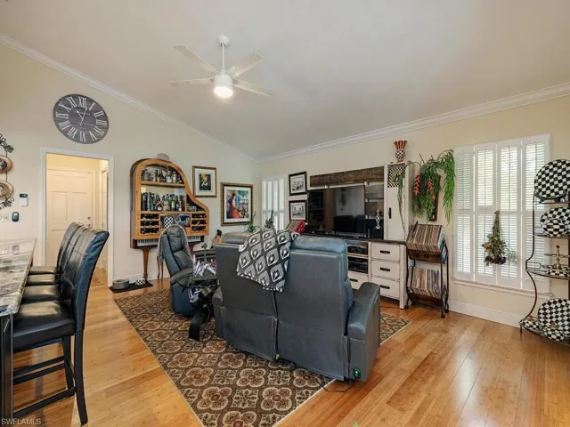 Living room featuring vaulted ceiling, ceiling fan, hardwood / wood-style floors, and crown molding