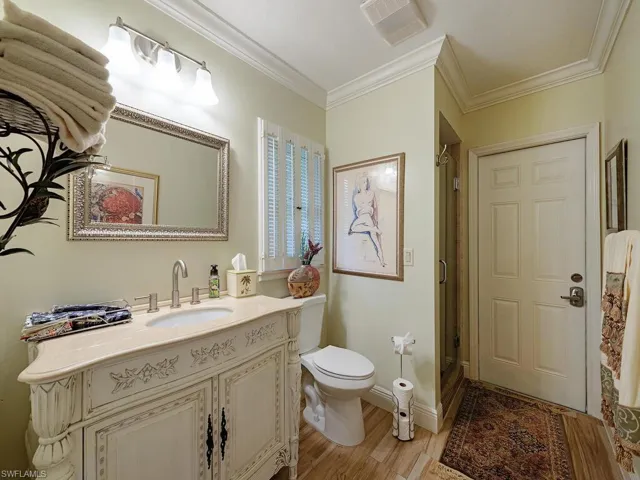 Bathroom with toilet, hardwood / wood-style floors, crown molding, vanity, and a shower with door