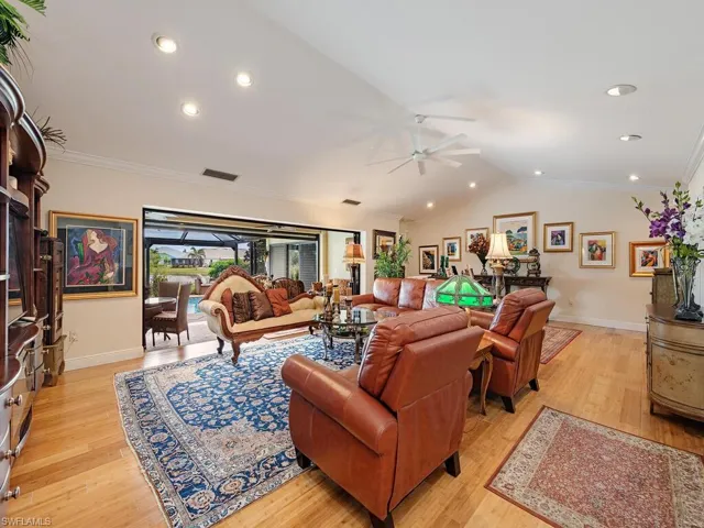 Living room featuring ceiling fan, light wood-type flooring, lofted ceiling, and ornamental molding