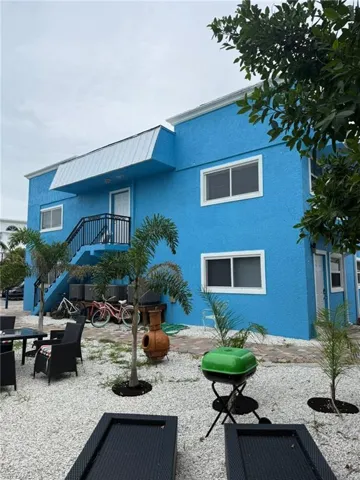 Rear view of property with stucco siding, stairway, and a patio