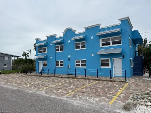 View of property with uncovered parking and stairs