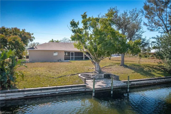 Back of property featuring a lawn, a sunroom, and a water view