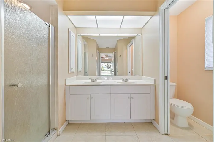 Bathroom featuring an enclosed shower, vanity, tile patterned floors, and toilet