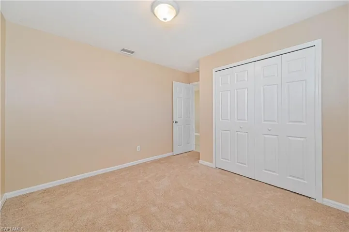 Unfurnished bedroom with light carpet and a closet