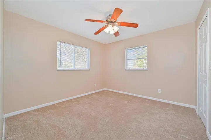 Carpeted empty room with ceiling fan and plenty of natural light