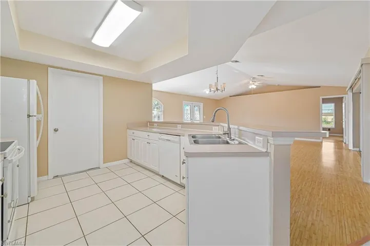 Kitchen featuring sink, white cabinets, kitchen peninsula, a healthy amount of sunlight, and white appliances