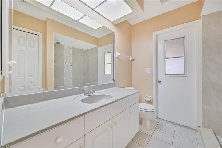 Bathroom with tile patterned floors, toilet, a shower, a skylight, and vanity