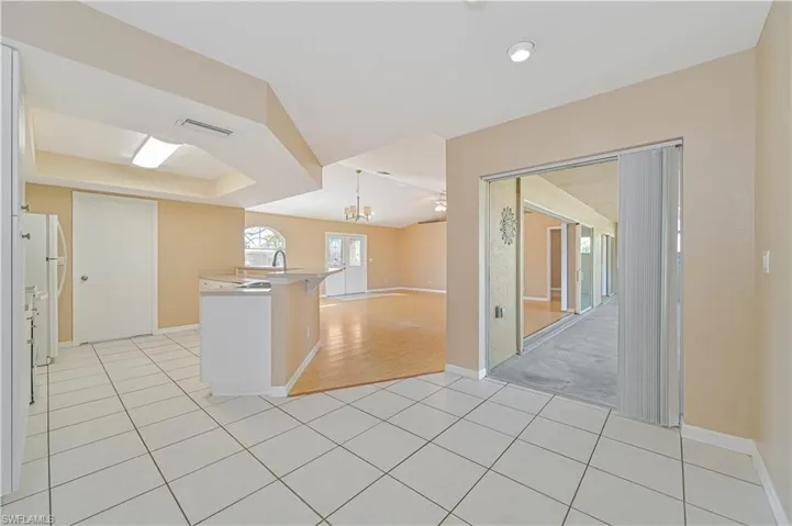 Kitchen with light tile patterned floors, sink, white refrigerator, a kitchen bar, and decorative light fixtures