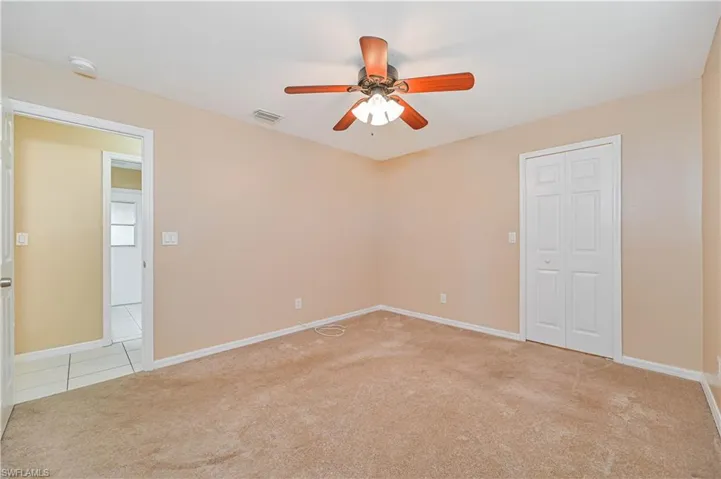 Empty room with light colored carpet and ceiling fan