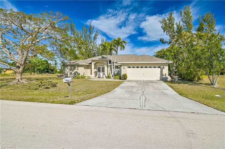 Ranch-style home featuring a garage and a front lawn