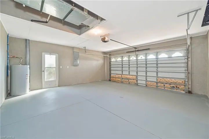 Garage featuring a garage door opener, electric panel, and water heater
