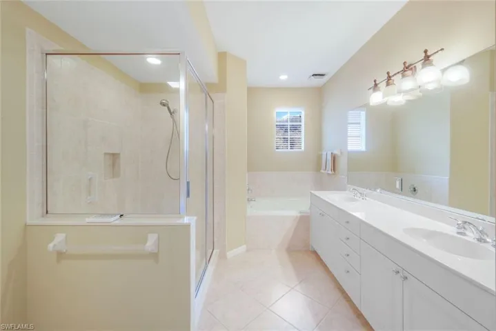 Full bath featuring double vanity, light tile patterned flooring, a shower stall, a bath, and recessed lighting