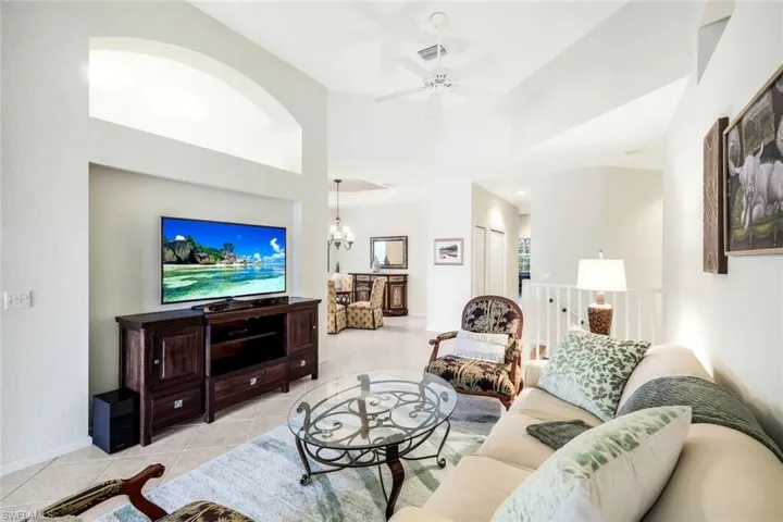 Living area featuring light tile patterned floors, ceiling fan, and a chandelier