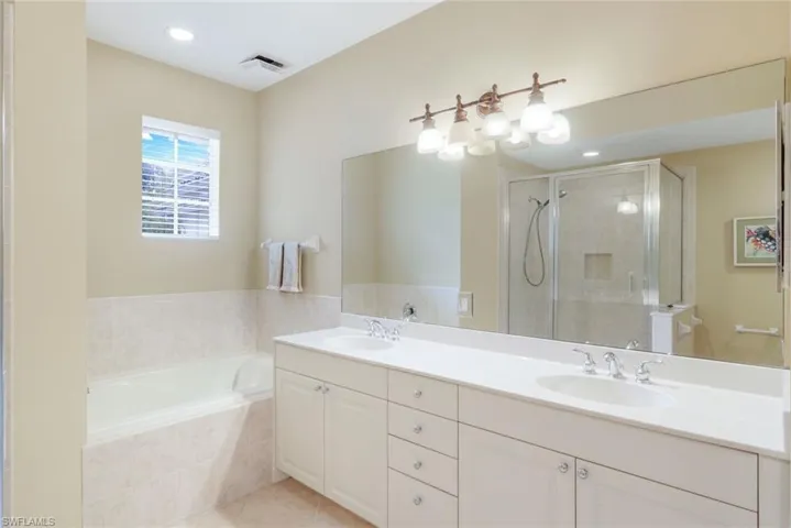 Full bathroom featuring double vanity, a stall shower, a bath, recessed lighting, and light tile patterned flooring