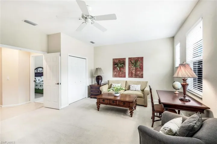 Carpeted living room with a ceiling fan and baseboards