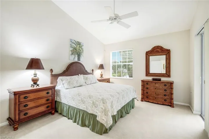 Bedroom with light carpet, a ceiling fan, and lofted ceiling