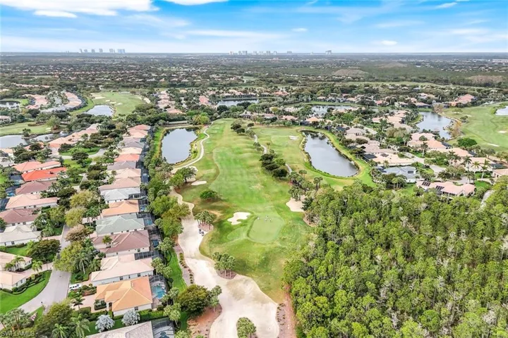 Aerial view of property and surrounding area with a golf club, a large body of water, and nearby suburban area