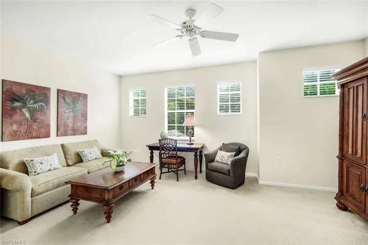 Living room with plenty of natural light, light colored carpet, a desk, and ceiling fan