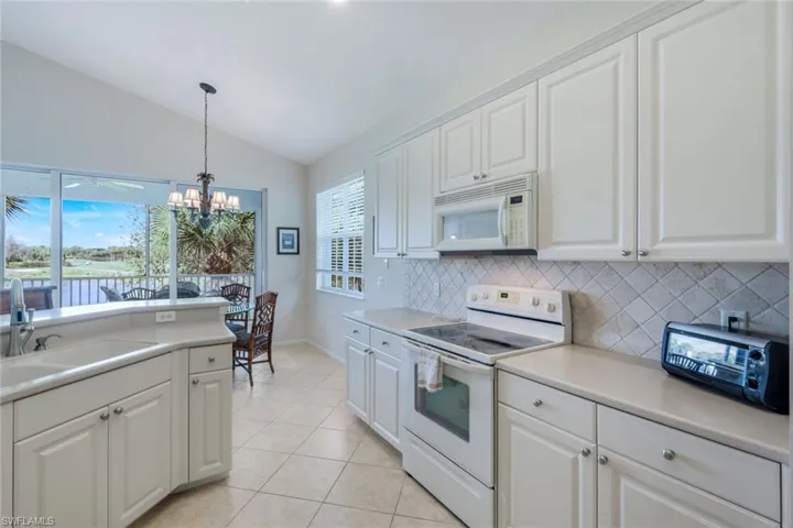 Kitchen featuring white appliances, white cabinets, and lofted ceiling
