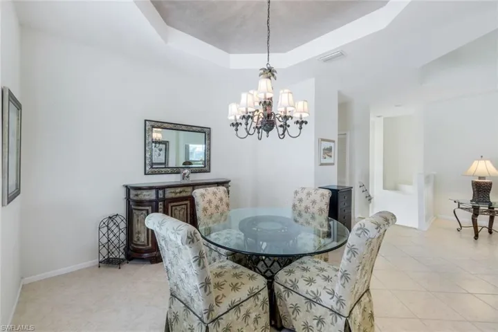 Dining space featuring a tray ceiling, light tile patterned floors, and a chandelier