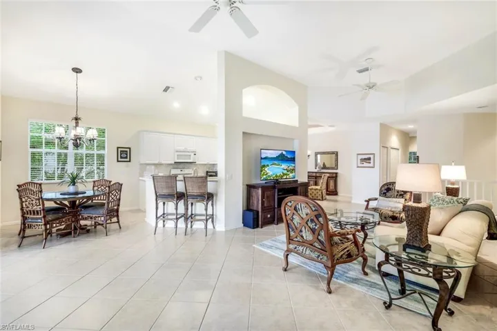 Living area with ceiling fan, light tile patterned flooring, a chandelier, and vaulted ceiling