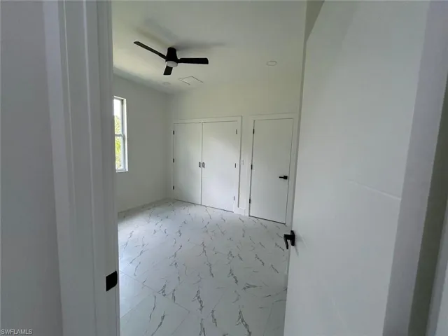 Unfurnished bedroom featuring marble look tile flooring and a ceiling fan