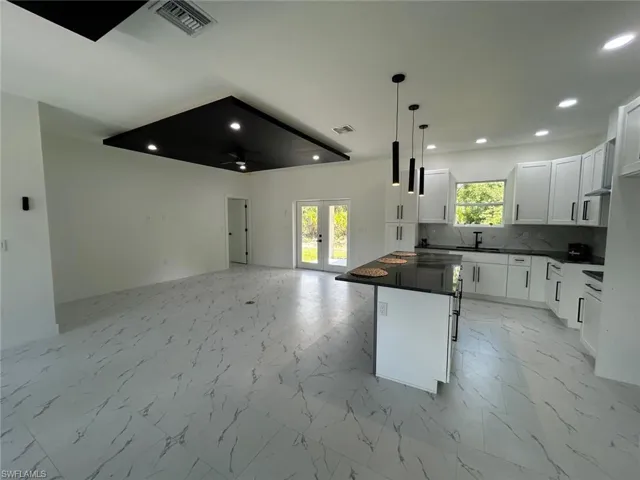 Kitchen with dark countertops, open floor plan, recessed lighting, french doors, and healthy amount of natural light
