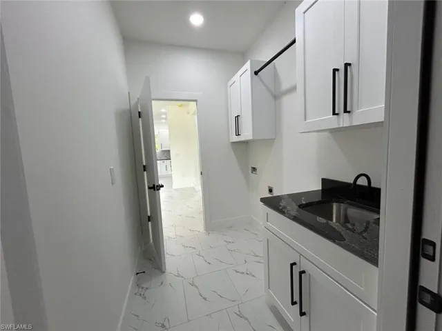 Washroom with electric dryer hookup, light marble finish flooring, cabinet space, and recessed lighting